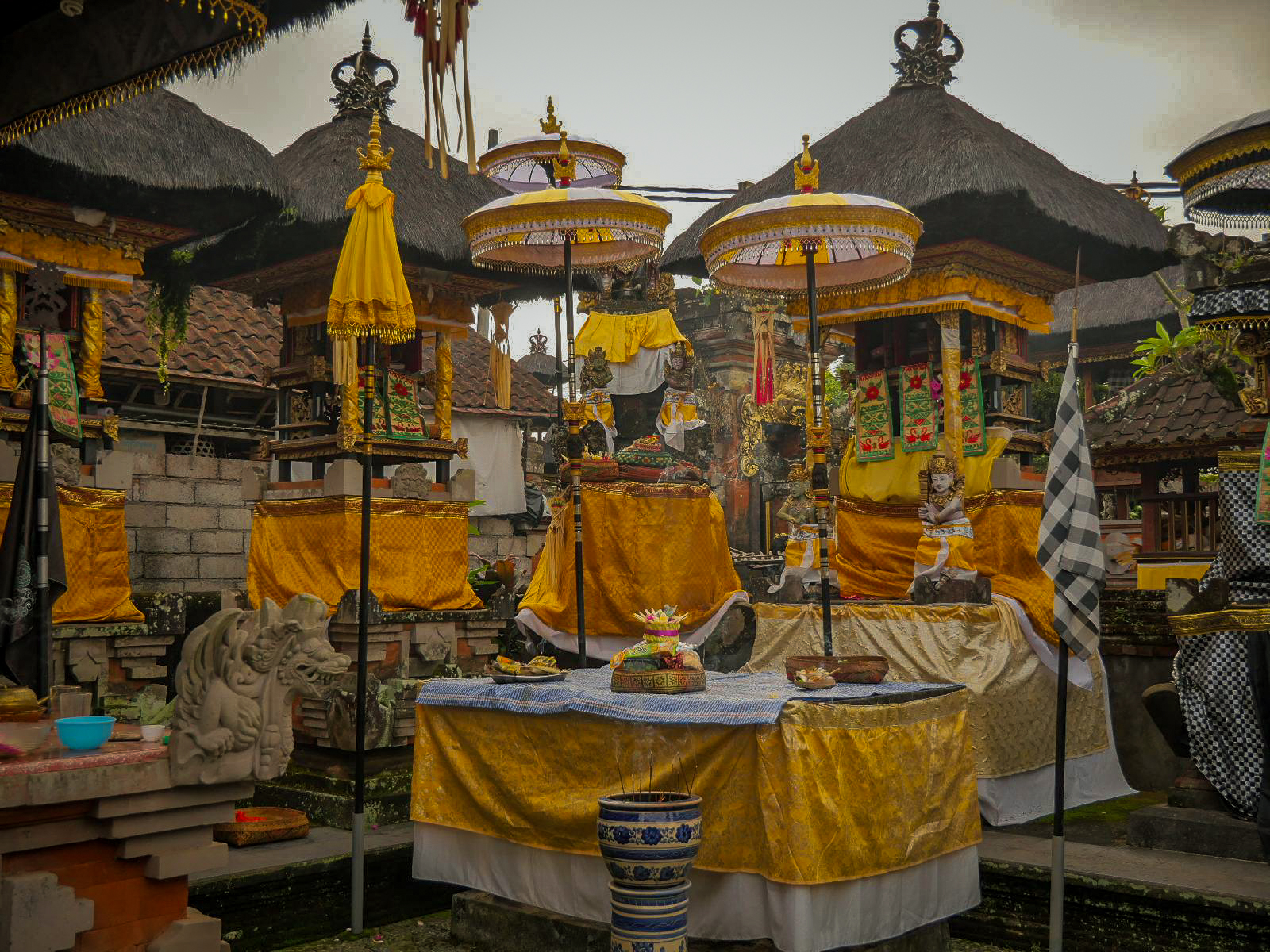 tempio balinese di famiglia allestito con tessuti gialli e bianchi e ombrelli tedung durante il Kuningan