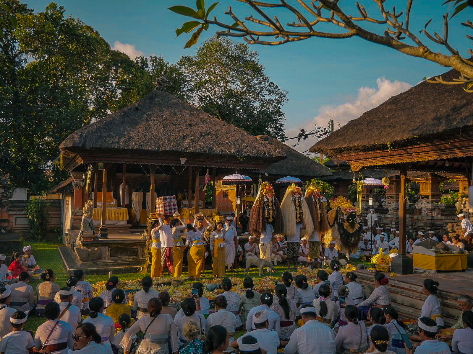 interno di un tempio balinese con persone sedute in preghiera e sullo sfondo barong e rangda